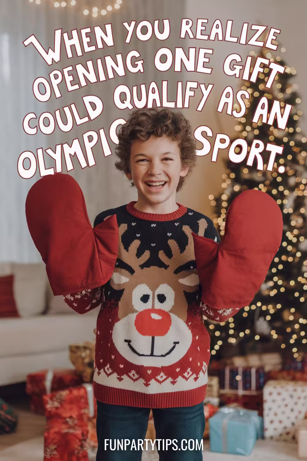 A-smiling-boy-wearing-a-reindeer-sweater-and-holding-giant-red-oven-mitts-in-a-festive-living-room-with-a-Christmas-tree-in-the-background.-The-text-reads-"When-you-realize-opening-one-gift-could-qualify-as-an-Olympic-sport."-oven-mitt-christmas-game.